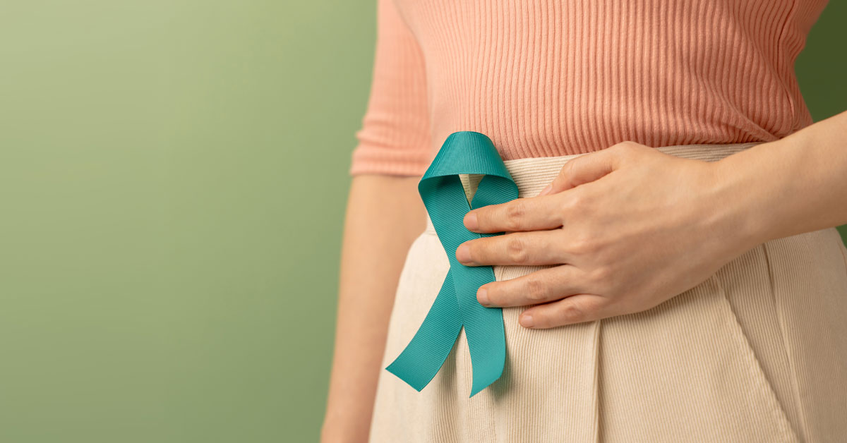 Woman with her hand on her abdomen holding a teal ribbon