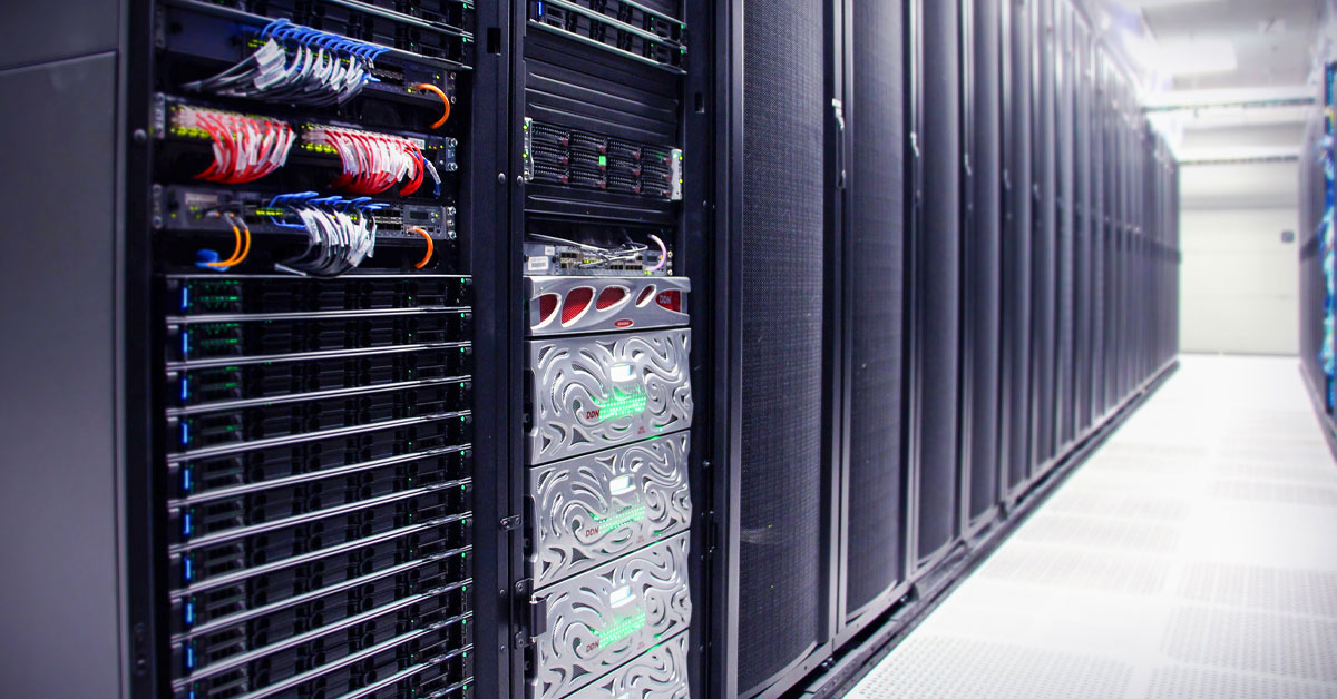An aisle of server racks in a data center, featuring cable management, lit indicators, and patterned metal storage units.