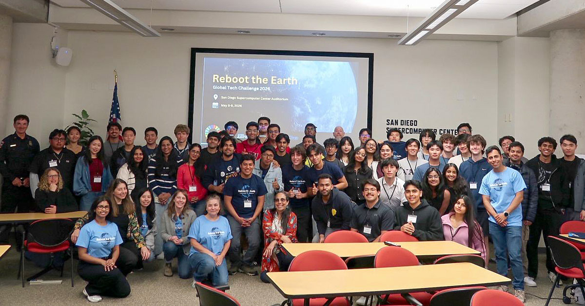 A group photo of students and organizers gathered in a lecture hall at the San Diego Supercomputer Center for the Reboot the Earth hackathon.