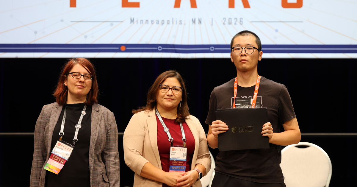 Three people on stage at PEARC in Minneapolis, MN 2026; a student on the right holds a best student paper award.