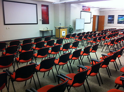 Rows of red and black chairs in an empty auditorium setting.